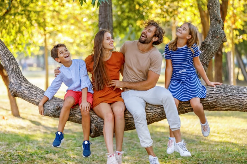 4 Factors to Consider When Buying a Heat Pump. Young Couple of Parents Enjoy with Son and Daughter in Nature During a Warm Sunny Day in a Natural Parkland.